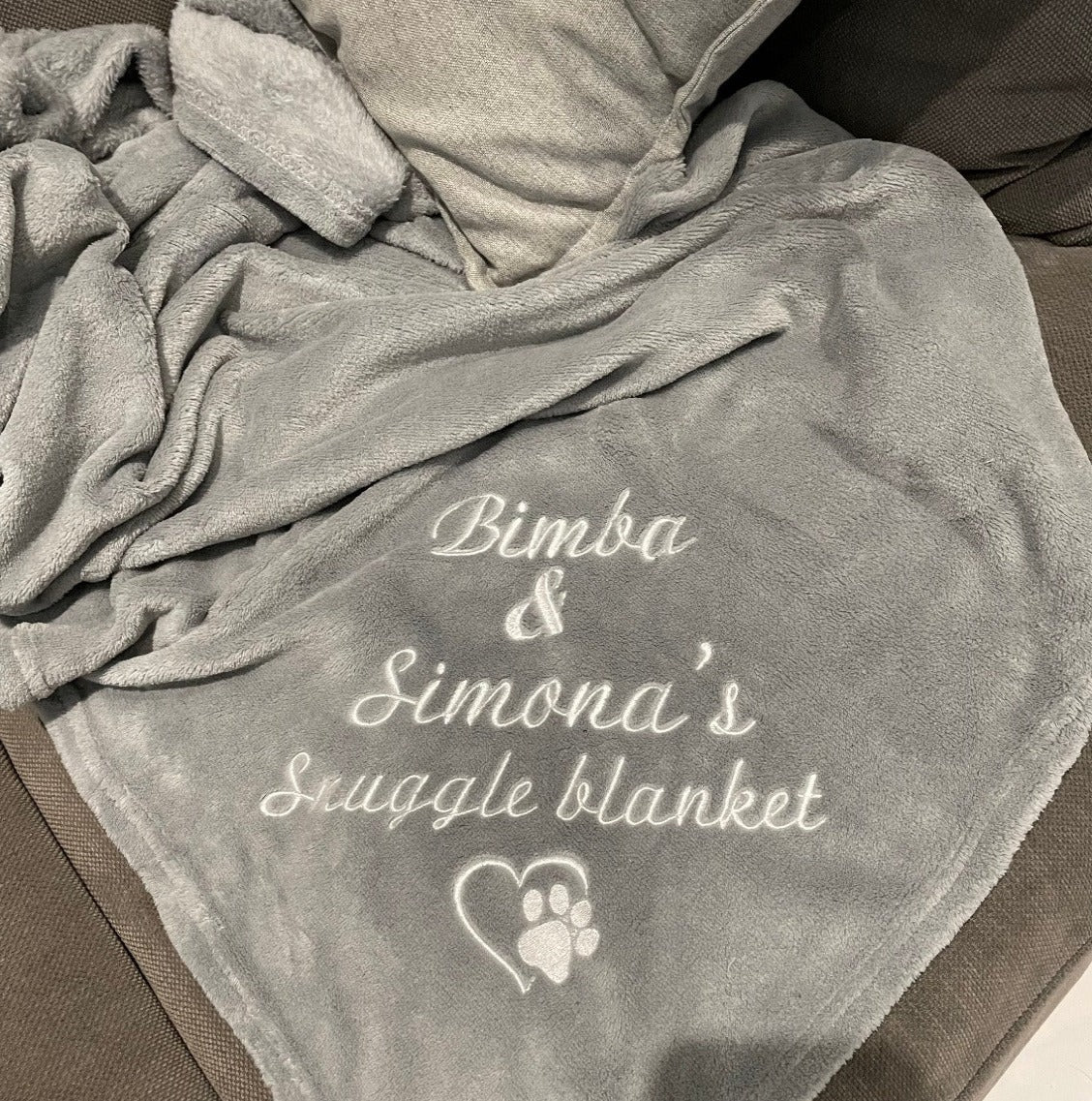 A cozy, personalized pet snuggle blanket with your furry friend's name embroidered on it